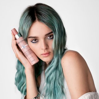 Portret. Dziewczyna z długimi, farbowanymi wielokolorowymi włosami w odcieniach niebieskiego. Ma klasyczny makijaż.