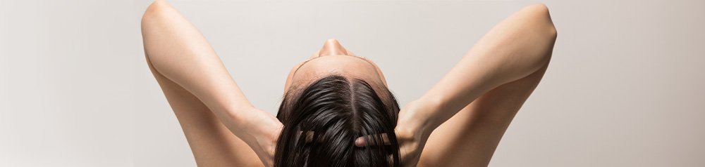 Kobieta myjąca włosy, z ramionami wzniesionymi nad głową