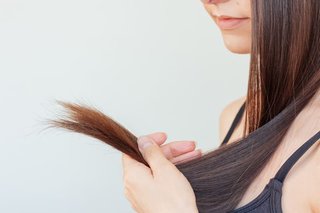 Zbliżenie na kobietę trzymającą w dłoni końcówki ciemnych włosów