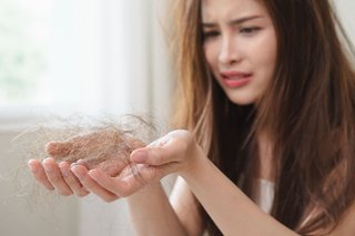 Kobieta trzymająca w garści wypadnięte włosy