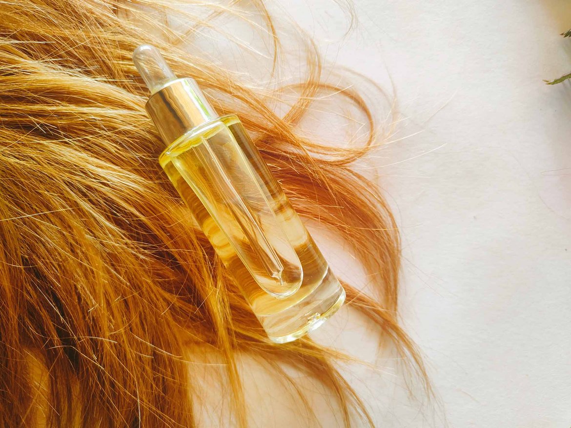 Długie włosy, na których leży kosmetyk do ich pielęgnacji