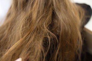 Zbliżenie na długie, brązowe włosy, które są przesuszone i mają zniszczone końcówki