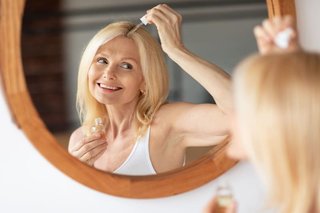 Kobieta w średnim wieku nakłada serum nawilżające na suchą skórę głowy