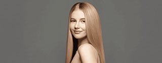 Portret młodej dziewczyny bez makijażu. Ma długie, proste, lśniące, gęste blond włosy.