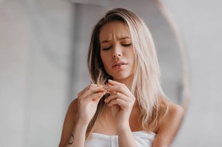 Młoda kobieta ogląda przesuszone końcówki włosów