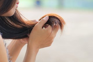 Kobieta trzymająca w dłoniach końcówki ciemnych prostych włosów