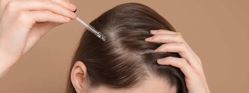 Kobieta nakłada serum na skalp głowy