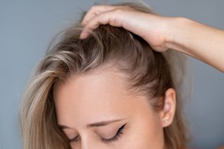 Kobieta odgarniająca dłonią z twarzy długie blond włosy
