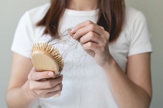 Kobieta wyciąga ze szczotki do włosów wypadnięte włosy