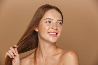 Uśmiechnięta młoda kobieta z długimi, zdrowo wyglądającymi rudymi włosami