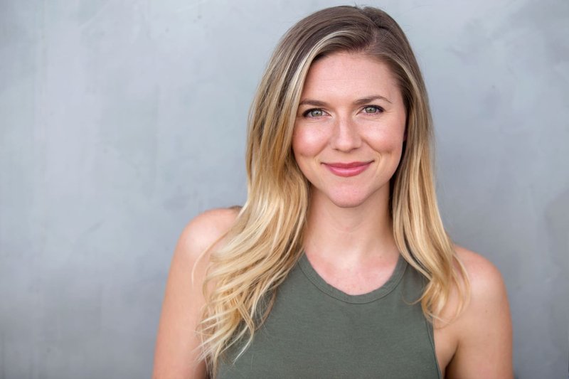 Młoda, uśmiechnięta kobieta z rozjaśnianymi włosami i w zielonej koszulce