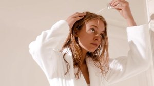 Kobieta aplikująca pipetą serum na skórę głowy