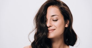 kobieta o ciemnych, zdrowo wyglądających włosach po kuracji pielęgnacyjnej włosów