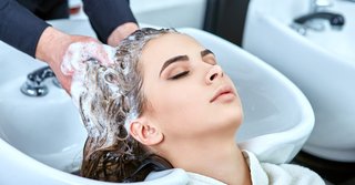 kobieta trzymająca swoje zdrowo wyglądające, lśniące włosy