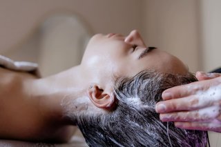 Zdjęcie przedstawiające mycie włosów młodej kobiety, wykonywane przez pracownika SPA